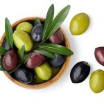 Delicious black, green and red olives with leaves in a wooden bowl, isolated on white background, view from above